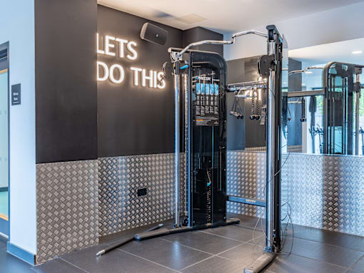 A gym with a black wall that says "Let's do this" and a row of exercise machines.