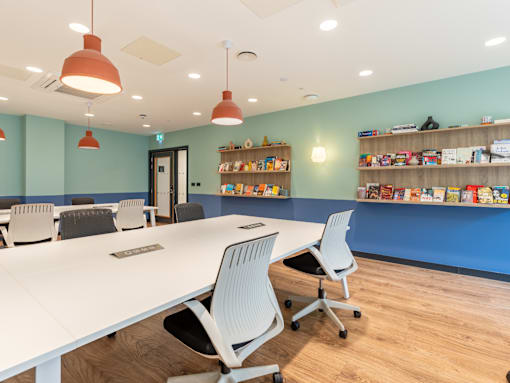 A room with a white table and chairs and a bookshelf filled with books.