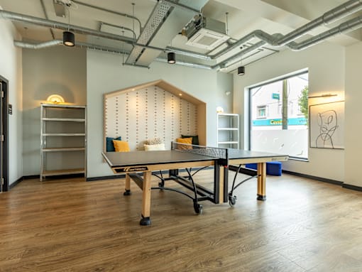 A room with a table and chairs in the center with a whiteboard on the wall.