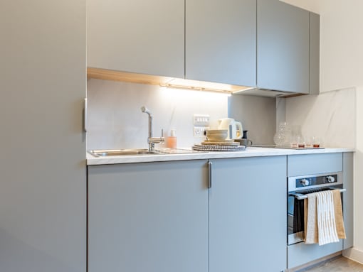A kitchen with a sink, a toaster, and a towel hanging on the oven.