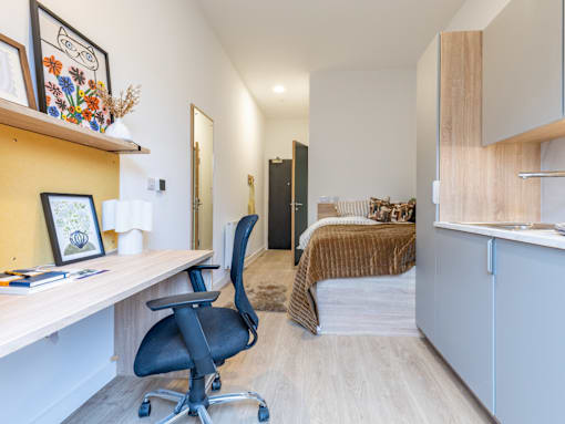 A room with a desk, chair, and bed.