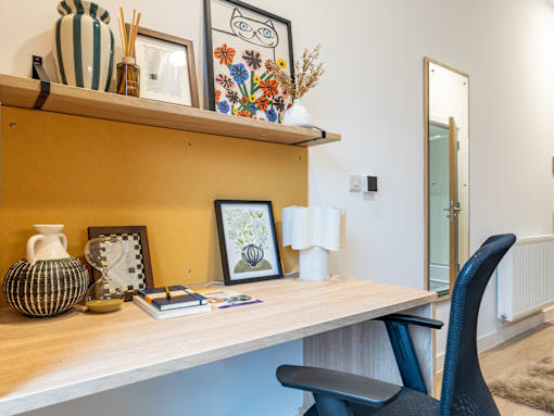 A desk with a chair and a shelf with decorative items.