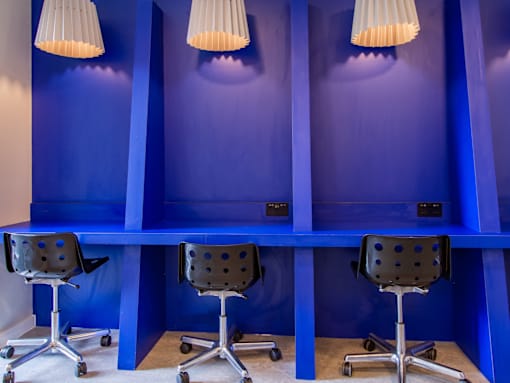 Three chairs are placed in front of a blue wall.