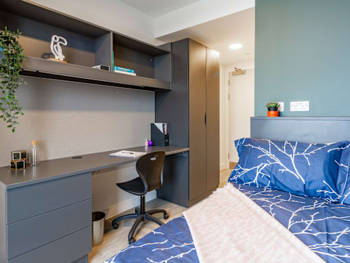 A bedroom with a bed, desk, and chair.