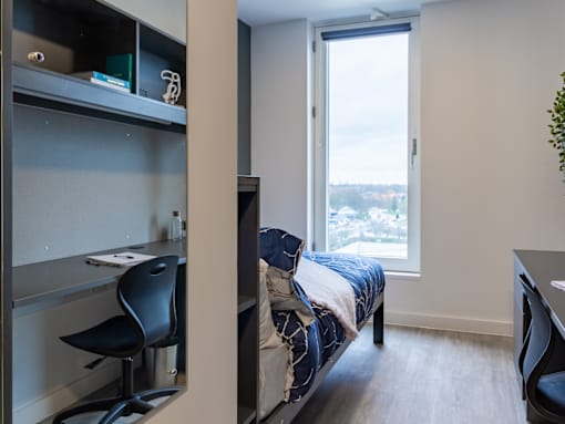 A bedroom with a bed, desk, and chair.