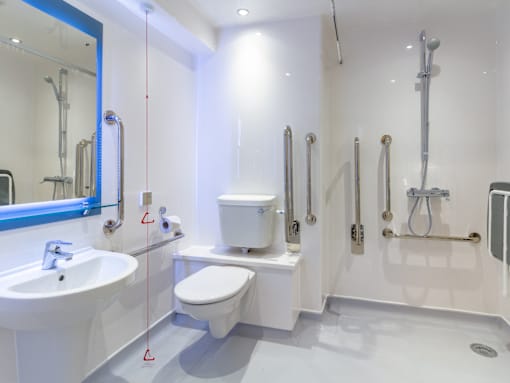 A white bathroom with a sink, toilet, and shower.