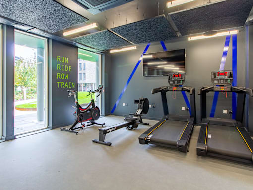 A gym with treadmills and a sign that says "Run, Ride, Row, Train".