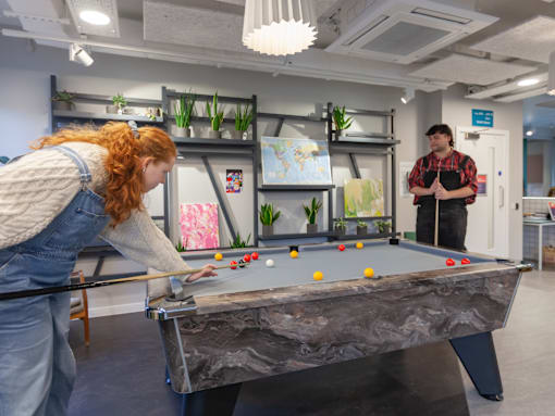 A woman playing pool in an office setting.