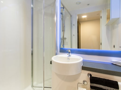 A white sink in a bathroom with a glass shower door.
