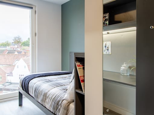 A bedroom with a bed and a small fridge.