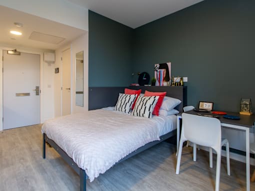 A bedroom with a bed, desk, and chair.