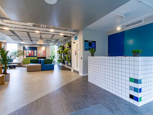 A modern office space with a blue tiled wall and a variety of seating options.