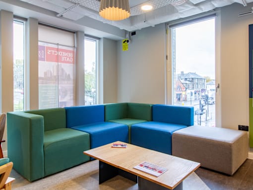 A blue and green sectional sofa in a room with a table and a chair.