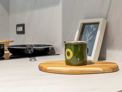 A green mug with a yellow label is on a wooden cutting board.