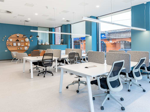 A modern office space with white desks and chairs.