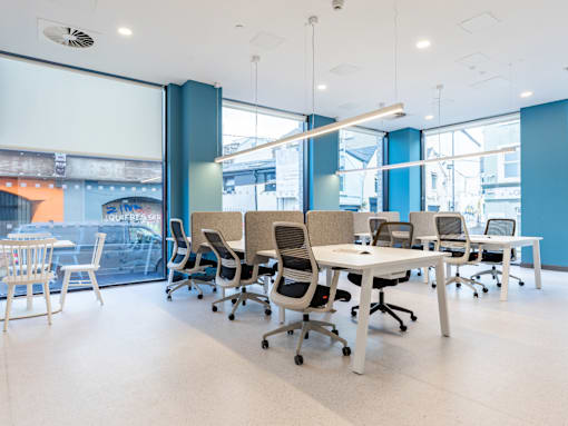 A room with white chairs and tables with a blue wall.