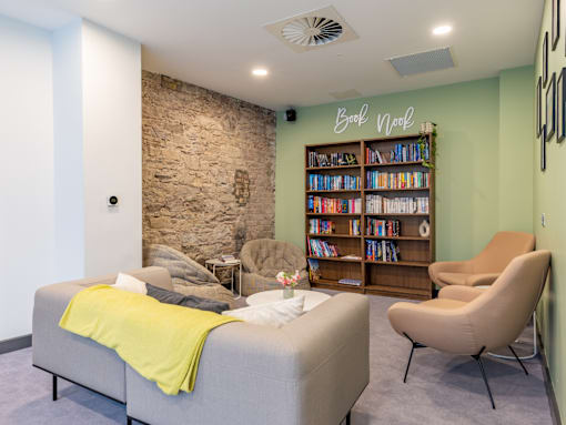 A room with a stone wall and a bookshelf filled with books.