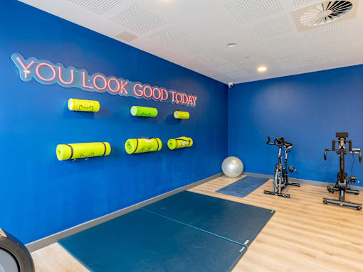A gym room with a blue wall and a neon sign that says "you look good today".