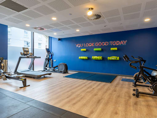 A gym with a blue wall and a neon sign saying "you look good today".