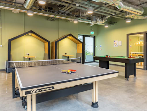 A ping pong table is in the middle of a room with mirrors on the wall.