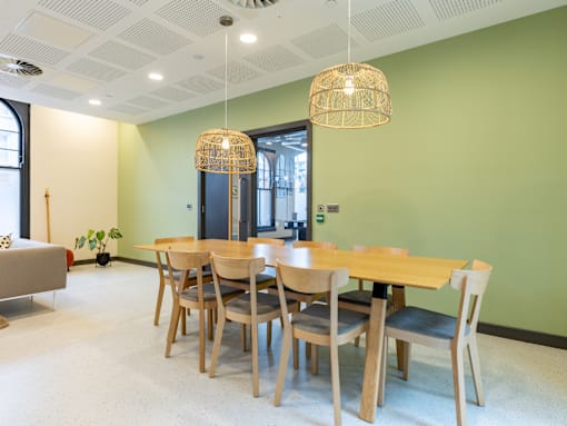 A room with a table and chairs and a hanging light fixture.