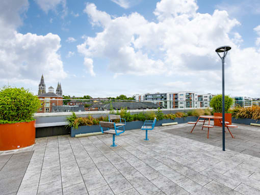 A rooftop patio with a table and chairs overlooking a cityscape.