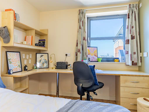 A bedroom with a desk and a chair.