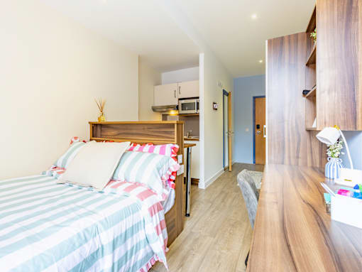 A bedroom with a bed, wooden furniture, and a striped bedspread.