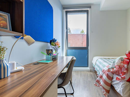 A room with a desk, chair, and bed.