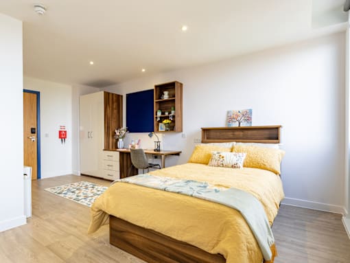 A bedroom with a bed, desk, and chair.