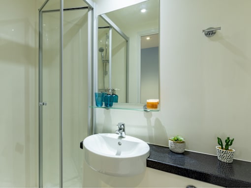 A white sink with a silver faucet and a mirror above it.