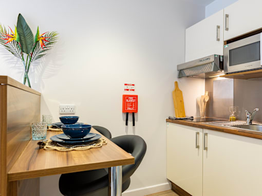 A kitchen with a table set for two and a vase of flowers on the table.
