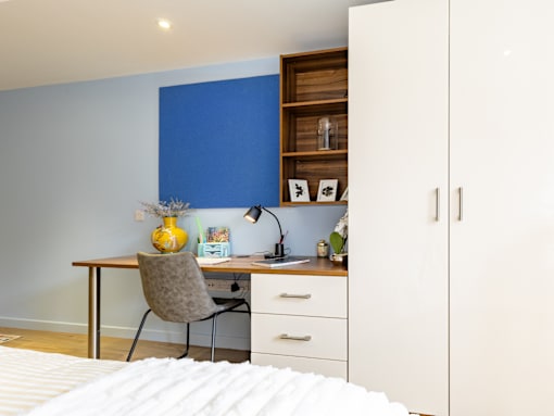 A room with a desk, chair, and bed.