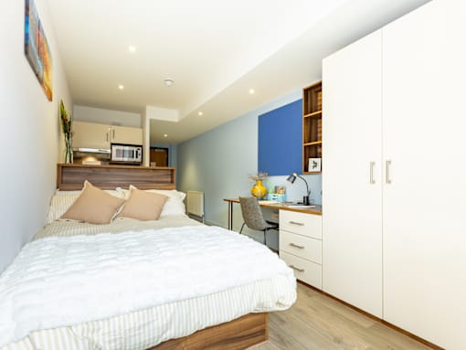 A bedroom with a large bed and a desk with a chair.