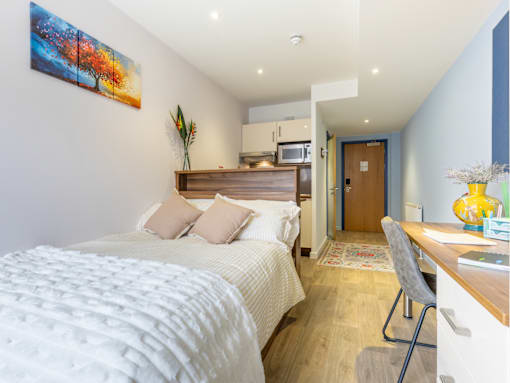 A bedroom with a large bed and a painting on the wall.