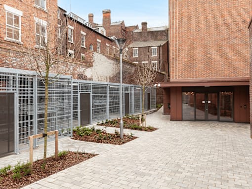 A courtyard with a brick building and a metal fence.
