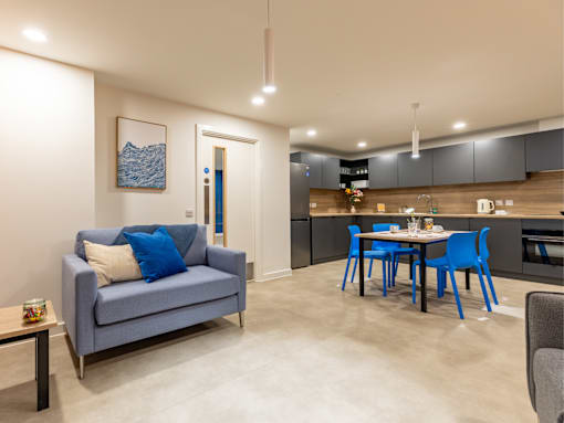 A blue couch with a pillow sits in a living room with a dining table and chairs.