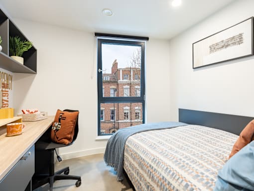 A bedroom with a bed, desk, and chair.