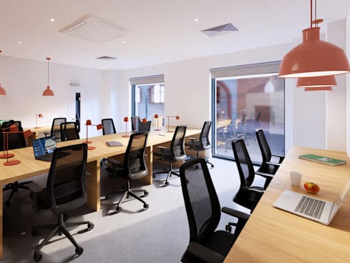 A row of black chairs are lined up in front of a row of desks with laptops on them.