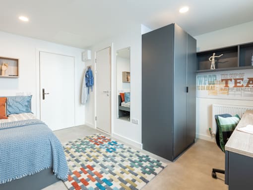 A bedroom with a bed, a wardrobe, and a chair.