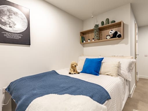 A bedroom with a bed, a teddy bear, and a poster of the moon.