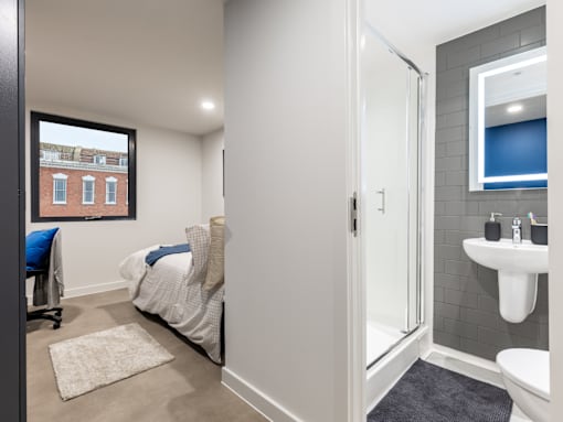 A bathroom with a white sink and a bedroom with a window.