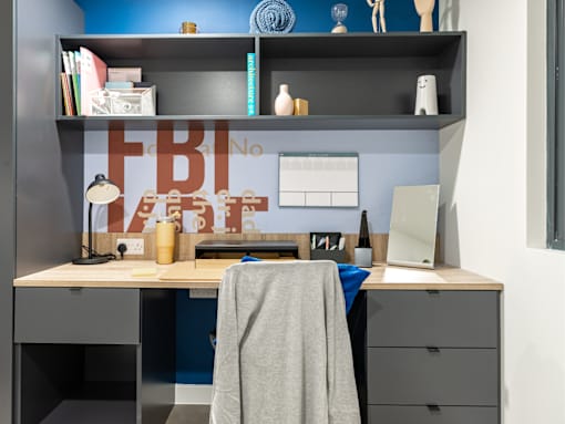 A workspace with a desk, chair, and shelves with various items.