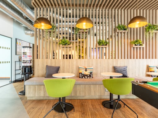 A modern room with a wooden ceiling and green chairs.