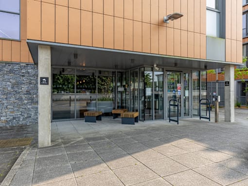 The image shows a building entrance with a glass door and a stone pillar.