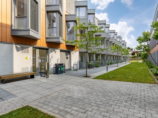 A long row of modern buildings with a bench in front of the first one.