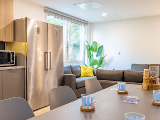 A modern kitchen with a stainless steel refrigerator and a dining table set for four.