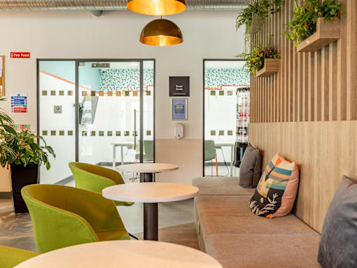 A room with a white table and green chairs.