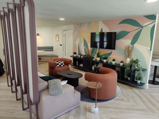 A living room with a pink couch and a TV on the wall.