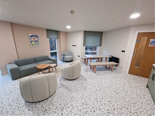 A room with a grey sofa, a white bean bag and a wooden table.
